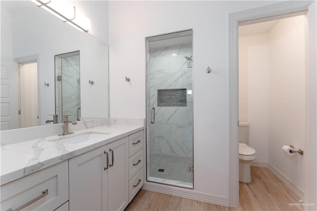 bathroom featuring a shower with door, vanity, wood-type flooring, and toilet