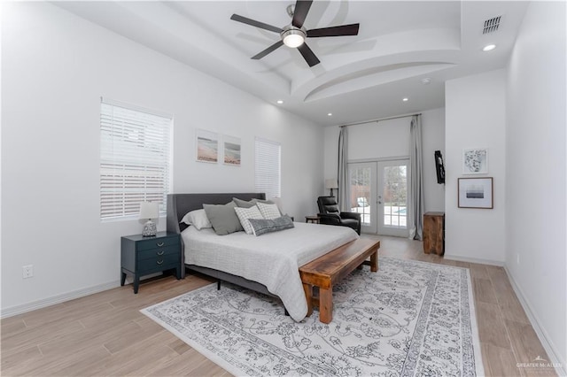 bedroom with french doors, light hardwood / wood-style flooring, a raised ceiling, ceiling fan, and access to exterior