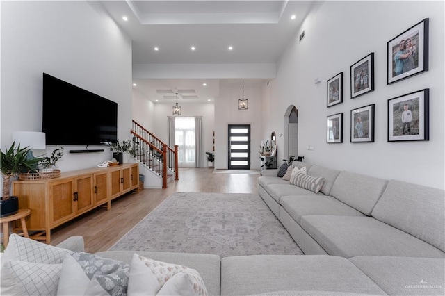 living room featuring a towering ceiling and light hardwood / wood-style floors