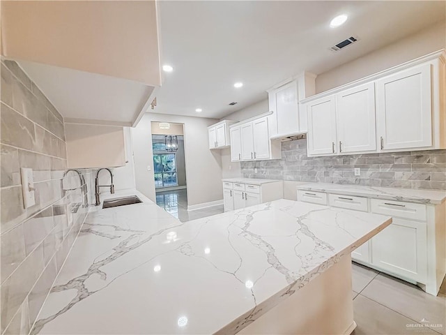 2817 Bluebird Ave, Mcallen, TX 78504 - kitchen featuring light stone countertops, a sink, decorative backsplash, white cabinetry, and recessed lighting