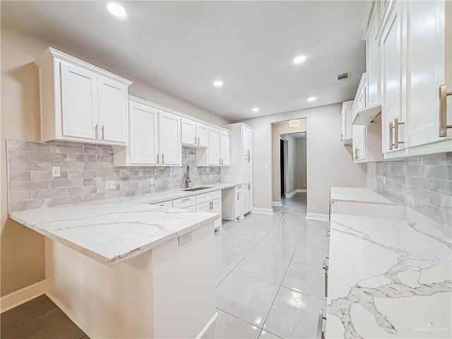 2817 Bluebird Ave, Mcallen, TX 78504 - kitchen featuring a peninsula, light stone countertops, a sink, baseboards, and white cabinetry
