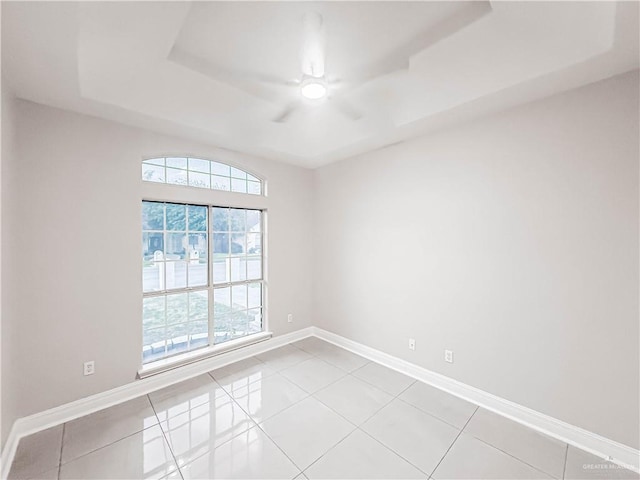 2817 Bluebird Ave, Mcallen, TX 78504 - spare room featuring a ceiling fan, a tray ceiling, light tile patterned flooring, and baseboards