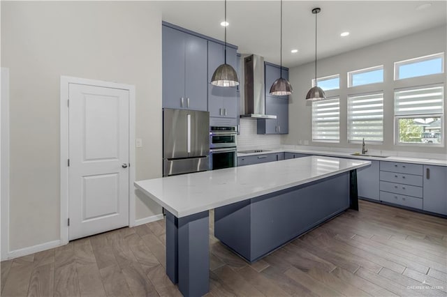 202 Constellation Dr E, Pharr, TX 78577 - kitchen featuring wall chimney range hood, stainless steel appliances, a kitchen island, decorative backsplash, and a breakfast bar