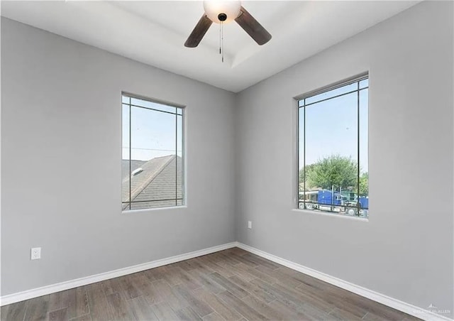 spare room featuring baseboards, wood finished floors, and a ceiling fan