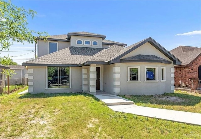 view of front of home featuring stucco siding, roof with shingles, a front yard, and fence