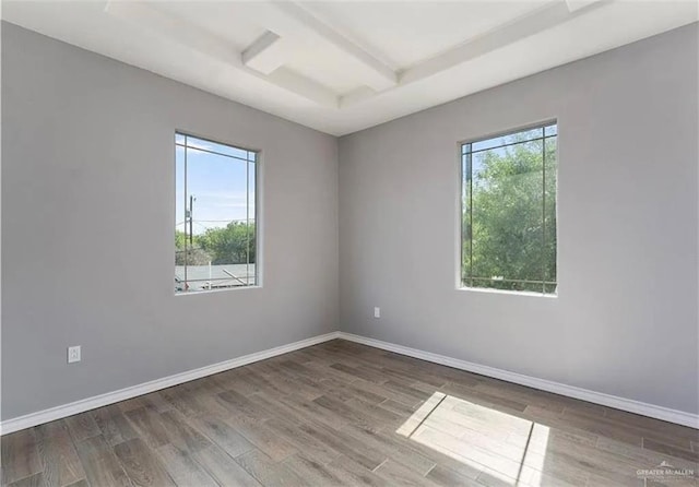 spare room featuring beam ceiling, coffered ceiling, baseboards, and wood finished floors