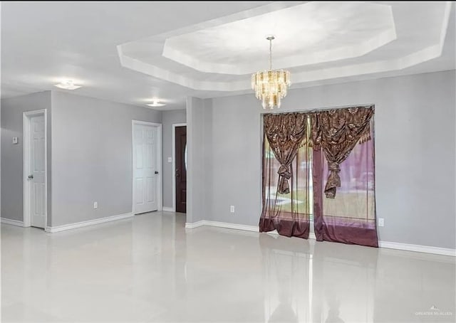 unfurnished room with baseboards, a raised ceiling, and a chandelier