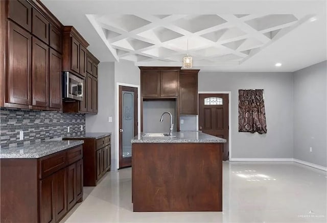 kitchen with stainless steel microwave, coffered ceiling, decorative backsplash, and a sink