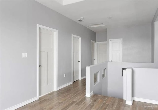 hall featuring an upstairs landing, visible vents, baseboards, and wood finished floors