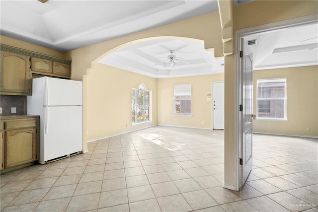 kitchen with light tile patterned floors, white fridge, a raised ceiling, and ceiling fan