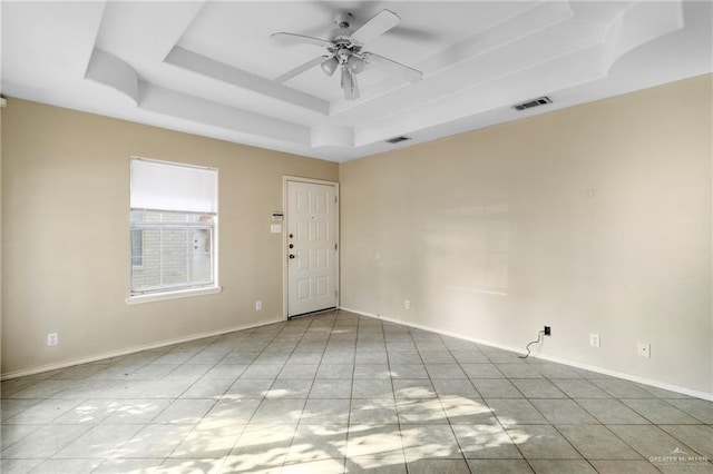 tiled spare room featuring a raised ceiling and ceiling fan