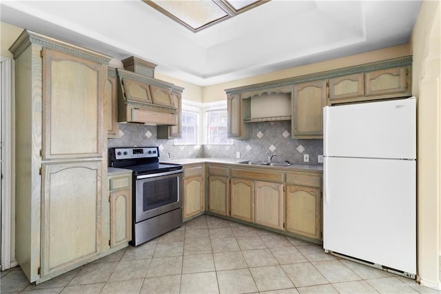 kitchen featuring a raised ceiling, sink, white fridge, and stainless steel range with electric stovetop