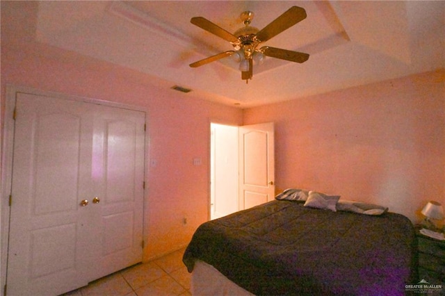 bedroom with a tray ceiling, ceiling fan, and light tile patterned floors