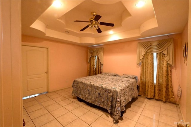 tiled bedroom with a tray ceiling and ceiling fan