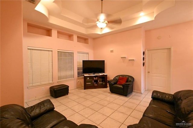 tiled living room featuring ceiling fan and a tray ceiling