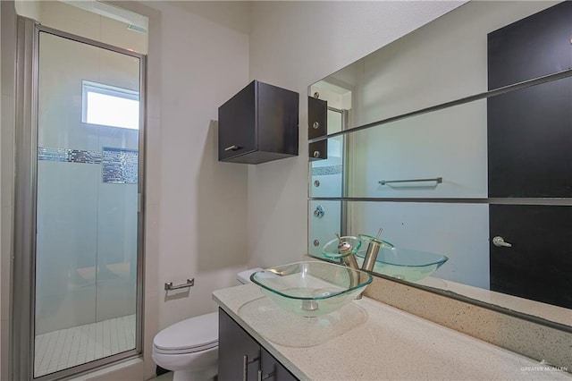 bathroom with a shower with door, vanity, and toilet