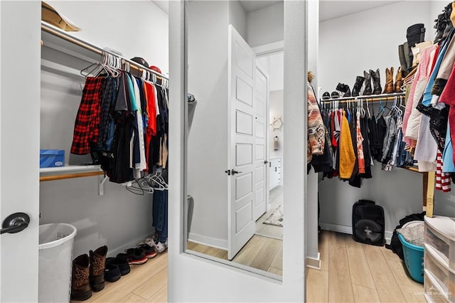 walk in closet with light hardwood / wood-style floors