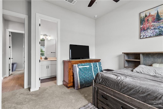 carpeted bedroom with ceiling fan, ensuite bath, and sink