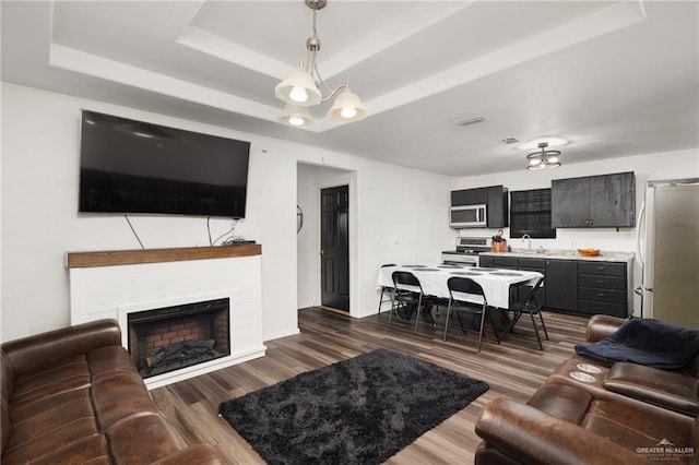 living room featuring a tray ceiling, dark hardwood / wood-style flooring, and sink