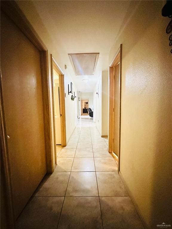 hall with attic access and light tile patterned floors