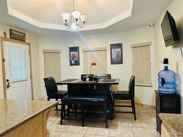 dining area featuring a raised ceiling, a notable chandelier, and light tile patterned floors