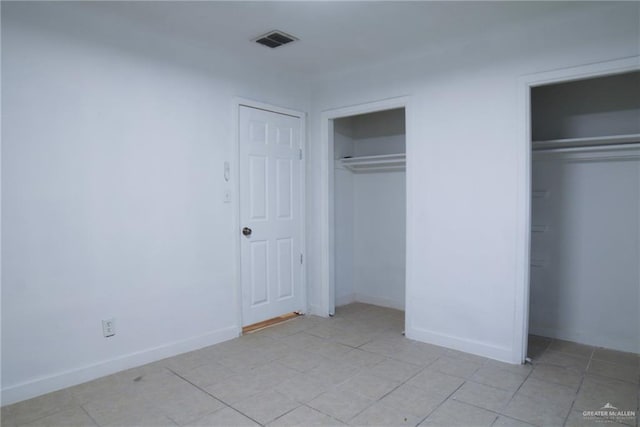 210 E Hurst St E, Harlingen, TX 78550 - unfurnished bedroom with multiple closets, light tile patterned floors, and baseboards