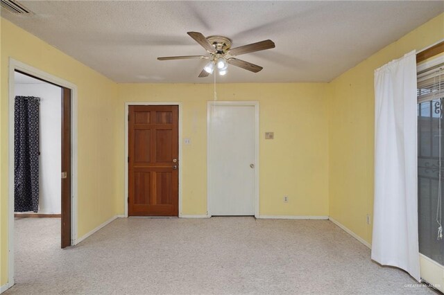 empty room with baseboards, visible vents, light carpet, and a ceiling fan
