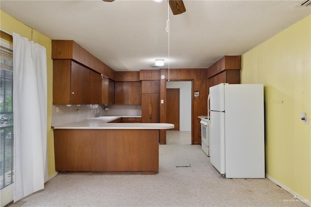kitchen featuring a sink, brown cabinetry, a peninsula, light countertops, and freestanding refrigerator