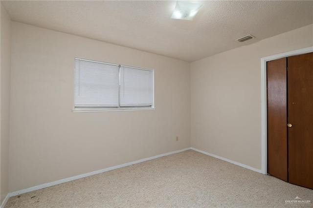 unfurnished bedroom with a closet, carpet, baseboards, visible vents, and a textured ceiling