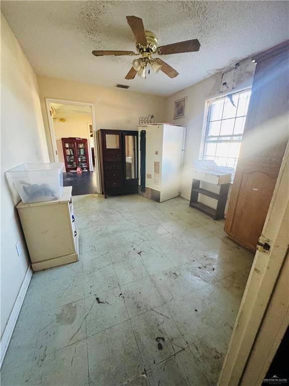 interior space with ceiling fan and a textured ceiling