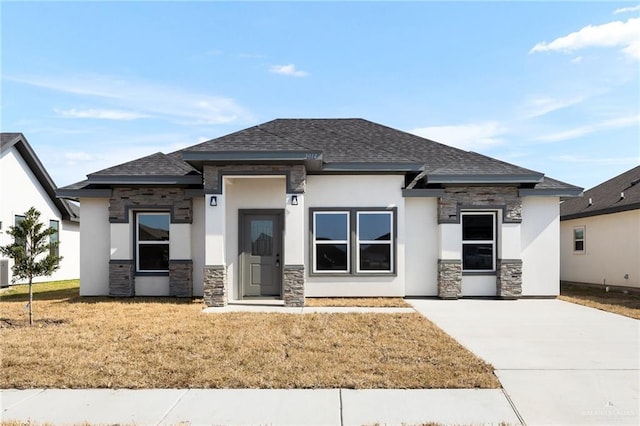 prairie-style home with stone siding, roof with shingles, and a front yard