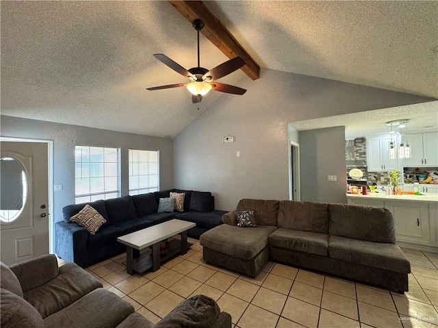 living area featuring a ceiling fan, vaulted ceiling with beams, a textured ceiling, and light tile patterned floors