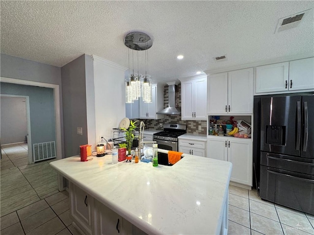 kitchen with visible vents, black fridge with ice dispenser, stainless steel gas range oven, and wall chimney exhaust hood