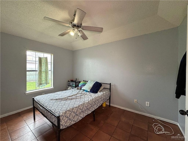 bedroom with dark tile patterned flooring, ceiling fan, a textured ceiling, and baseboards