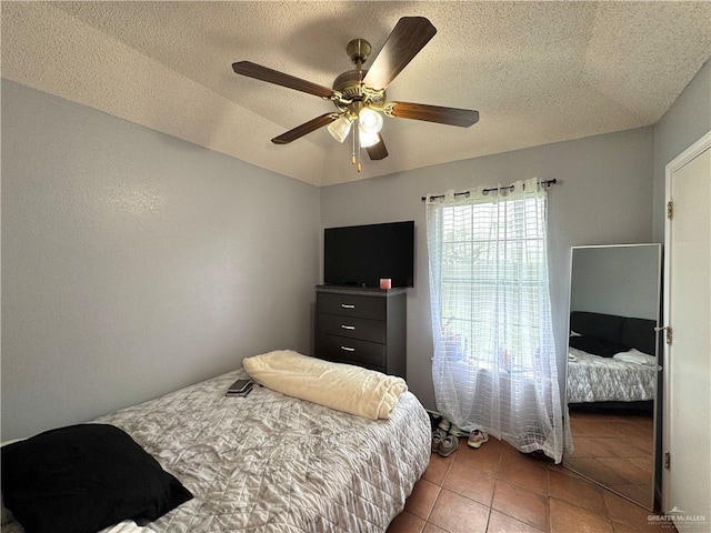 bedroom featuring ceiling fan, a textured ceiling, and tile patterned floors