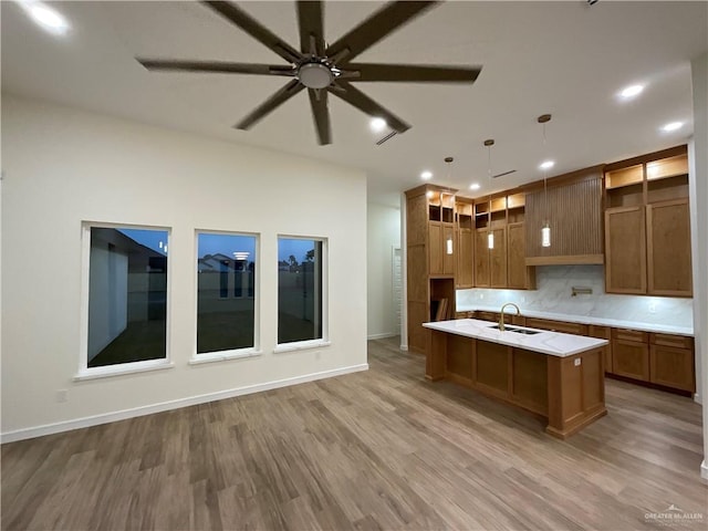 1513 Helen Dr, Weslaco, TX 78596 - kitchen with a sink, light wood-style floors, brown cabinets, a center island with sink, and light countertops