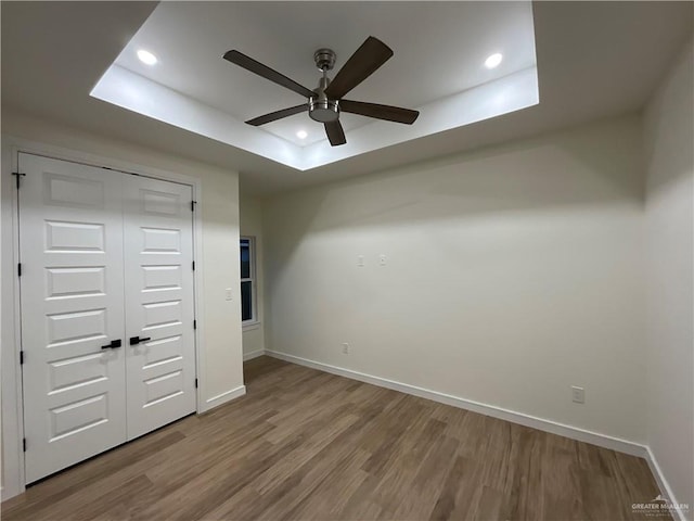 1513 Helen Dr, Weslaco, TX 78596 - unfurnished bedroom with wood finished floors, a tray ceiling, baseboards, recessed lighting, and a closet
