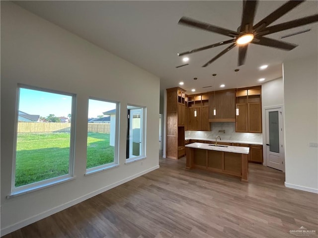 1513 Helen Dr, Weslaco, TX 78596 - kitchen with a sink, wood finished floors, light countertops, decorative backsplash, and a kitchen island with sink