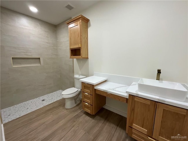1513 Helen Dr, Weslaco, TX 78596 - full bathroom featuring wood finished floors, toilet, vanity, and tiled shower
