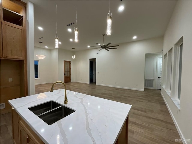 1513 Helen Dr, Weslaco, TX 78596 - kitchen featuring a sink, light wood finished floors, light stone counters, hanging light fixtures, and ceiling fan