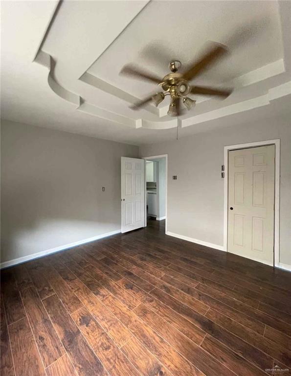 2708 Hackberry St, Weslaco, TX 78596 - unfurnished room featuring a raised ceiling, dark wood-style floors, a ceiling fan, and baseboards