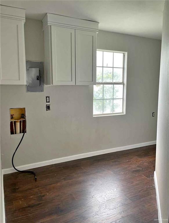 2708 Hackberry St, Weslaco, TX 78596 - washroom with washer hookup, baseboards, electric panel, dark wood finished floors, and cabinet space