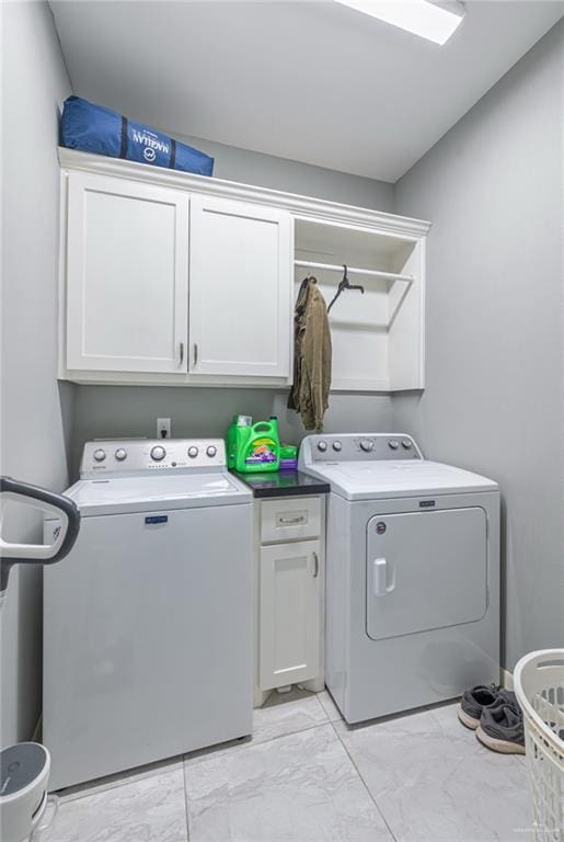 clothes washing area with marble finish floor, independent washer and dryer, and cabinet space