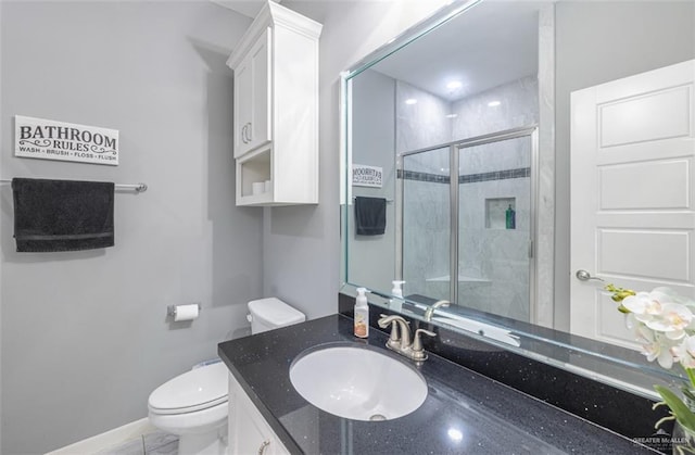 bathroom with vanity, a shower stall, toilet, and baseboards