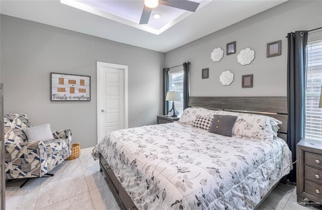 bedroom with ceiling fan and a tray ceiling