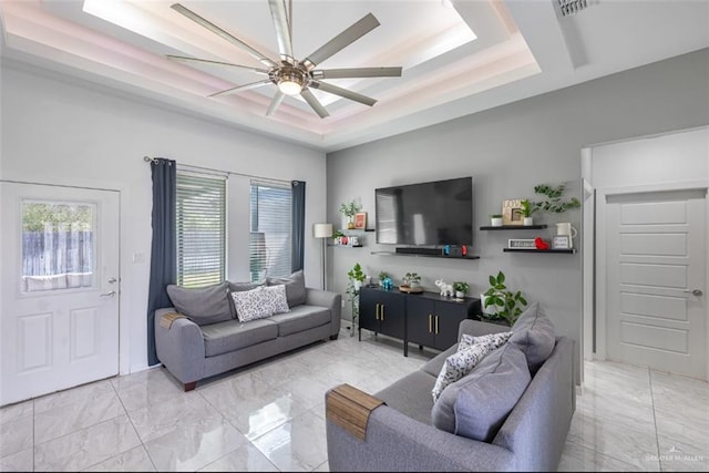 living area featuring marble finish floor, ceiling fan, and a raised ceiling