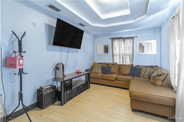 living room featuring hardwood / wood-style flooring and a raised ceiling