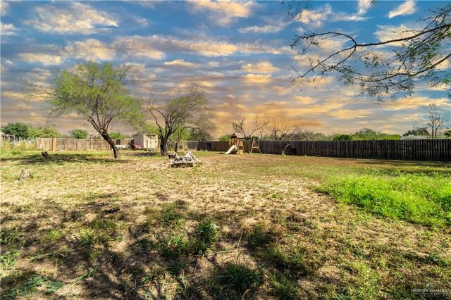 yard at dusk featuring a playground