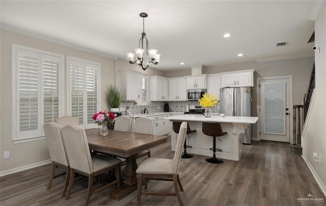 dining room with a chandelier, ornamental molding, and dark wood-type flooring