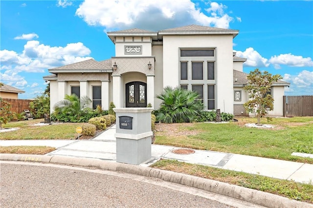 prairie-style home featuring fence, a front lawn, french doors, and stucco siding